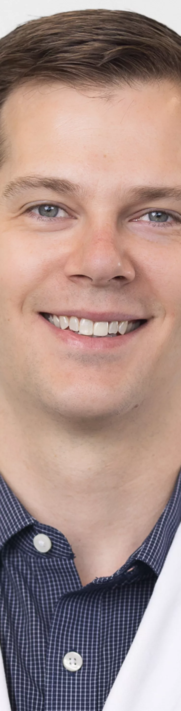 Headshot of David Henderson. He is wearing a blue dress shirt and a white coat.