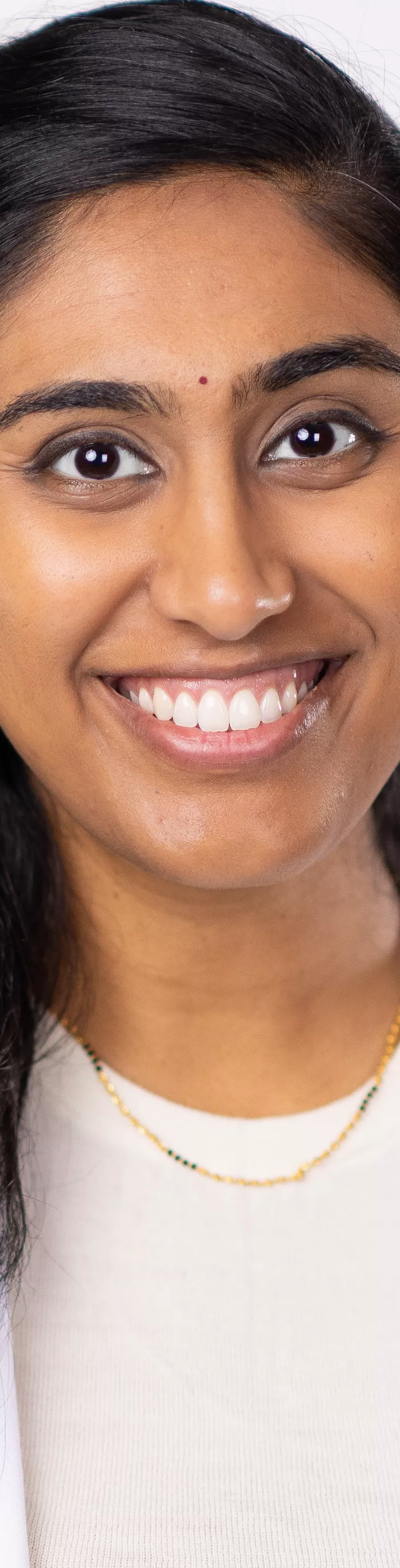 Headshot of Divya Rayapati. She is wearing a cream colored sweater and a white coat.