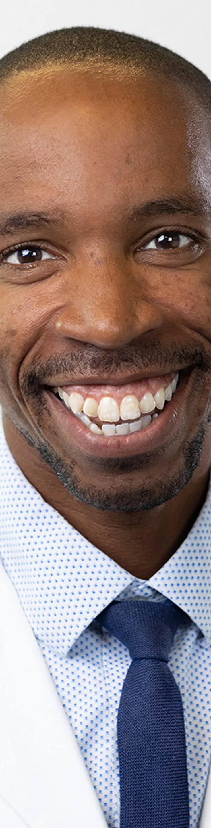 Headshot of Duriel Hardy. He is wearing a light blue dress shirt, a dark blue tie, and a white coat.