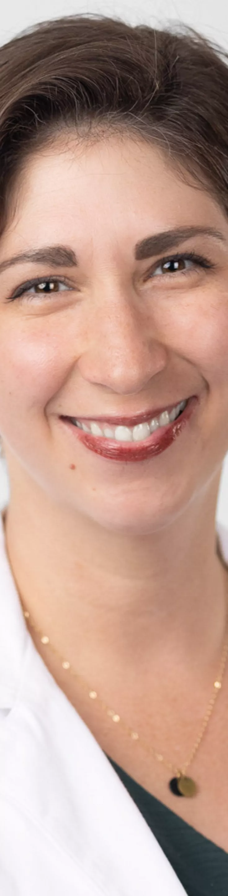 Headshot of Elizabeth Rosenthal. She is wearing a green blouse and a white coat.