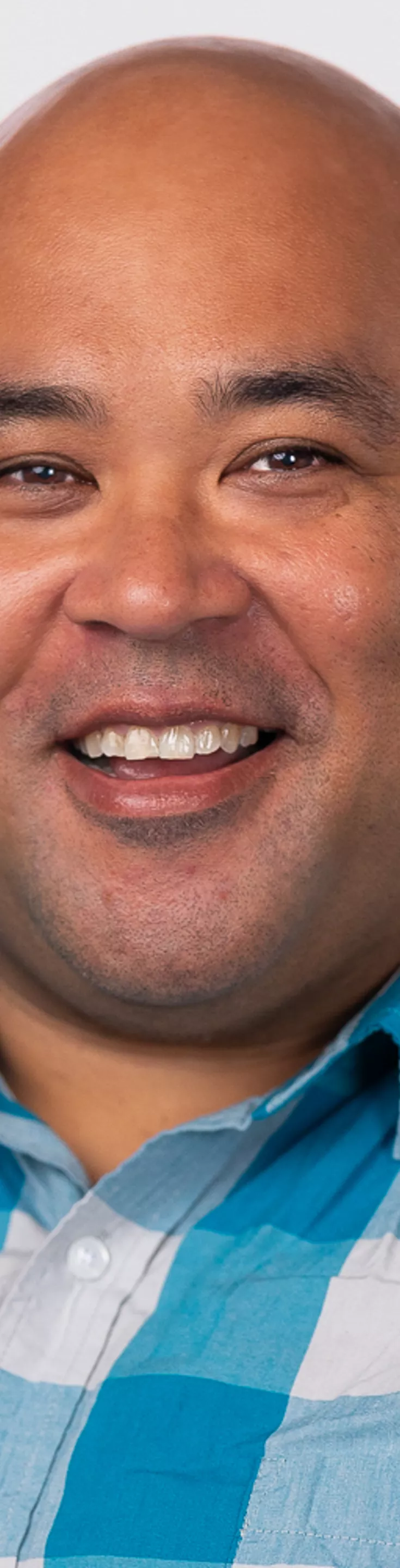 Headshot of Geoffrey Vasile. He is wearing a blue checkered dress shirt.