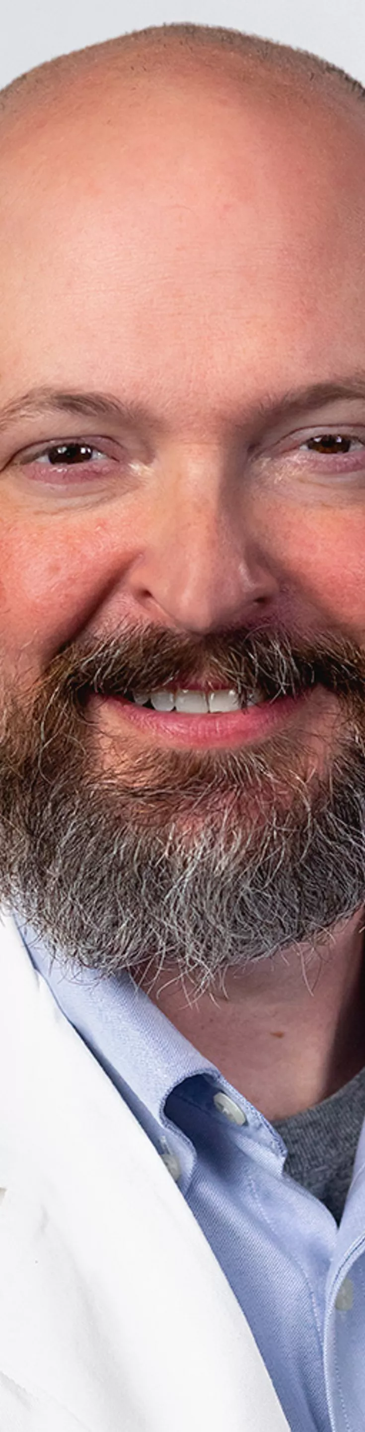 Headshot of Jared Benge. He is wearing a blue dress shirt and a white coat.