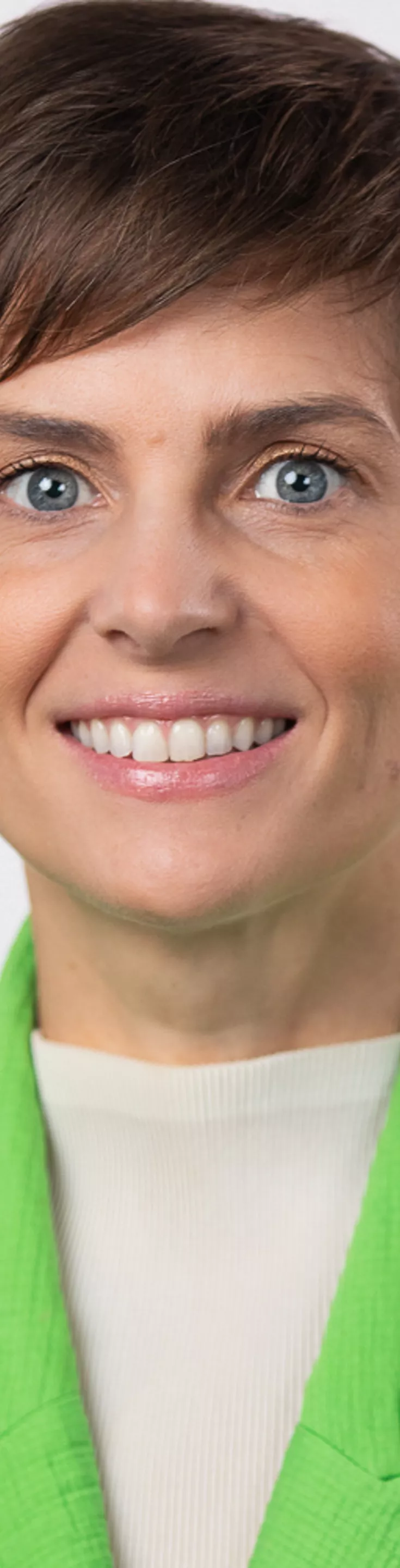 Headshot of Jeni Wade. She is wearing a white sweater and a lime green blazer.