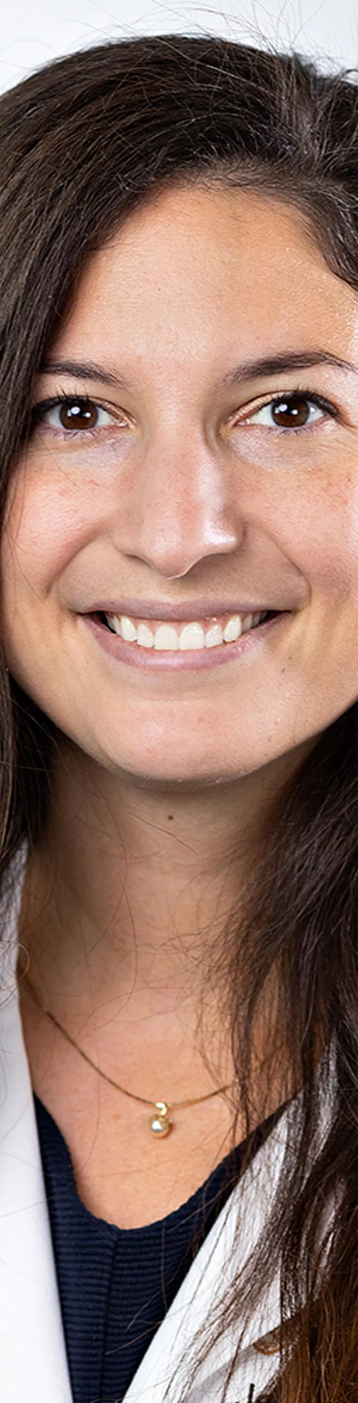 Heashot of Jenny Travieso. She is wearing a black blouse and a white coat.