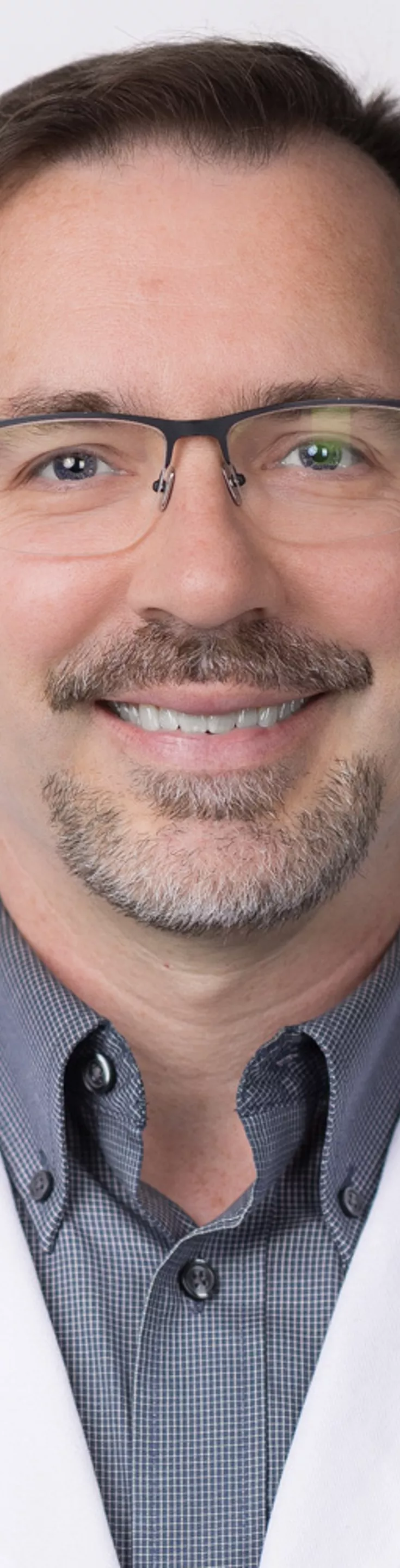 Headshot of Jon Willie. He is wearing a gray dress shrit and a white coat.