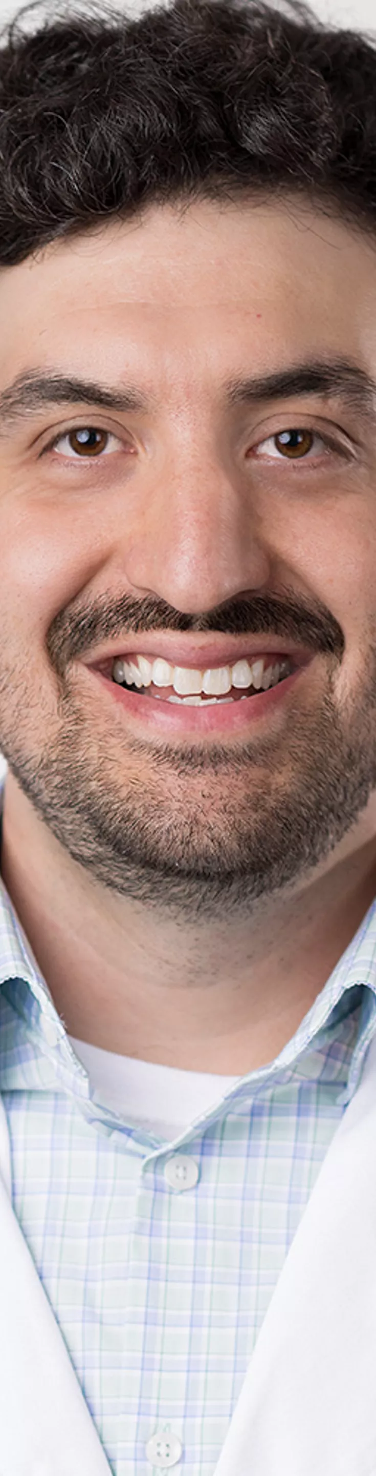Headshot of Jordan Jacquez. He is wearing a blue dress shirt and a white coat.