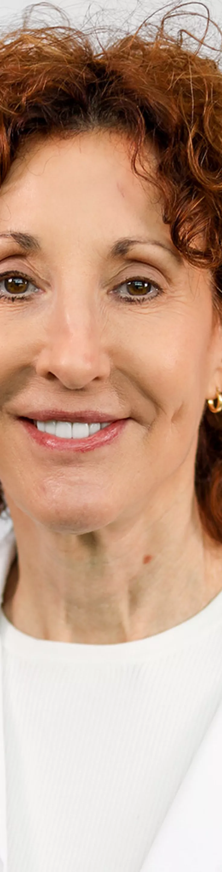 Headshot of Julie Farrington. She is wearing a white blouse and a white coat.