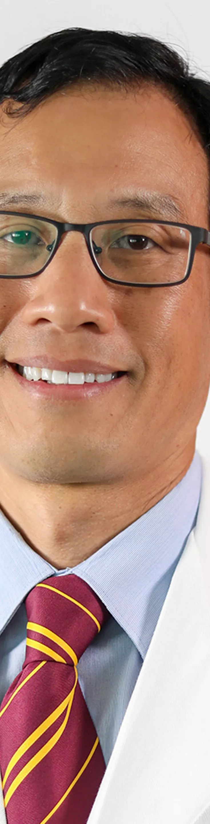 Headshot of Karl Chiang. He is wearing a light blue shirt, a yellow and red striped tie, and a white coat.