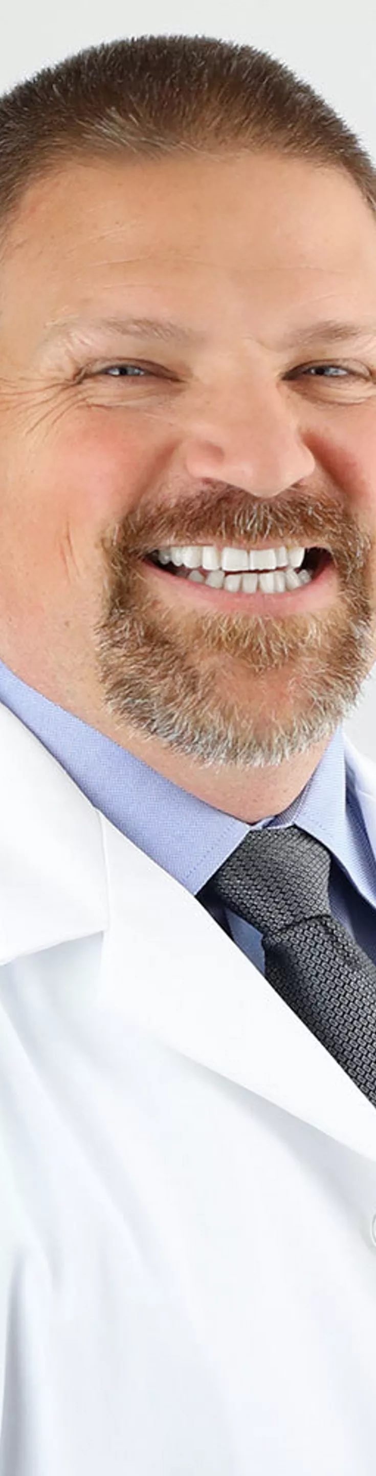 Headshot of Karl Koenig.  He is wearing a white coat and a gray tie.