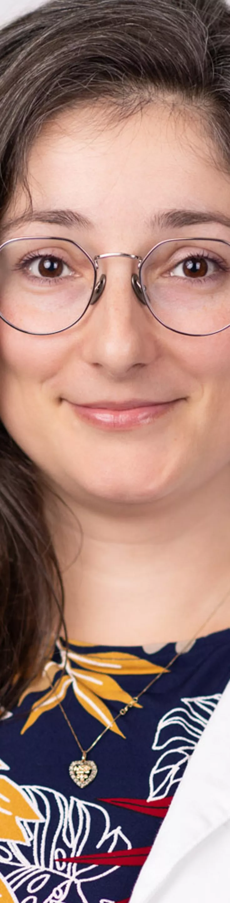 Headshot of Kristina Tzartzeva. She is wearing a multicolored blouse and a white coat.