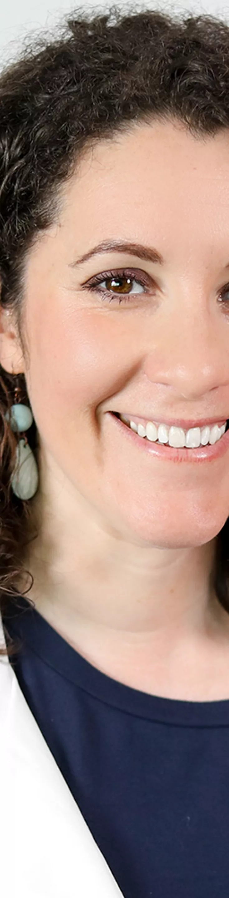 Headshot of Leora Freeman. She is wearing a navy blouse and a white coat.