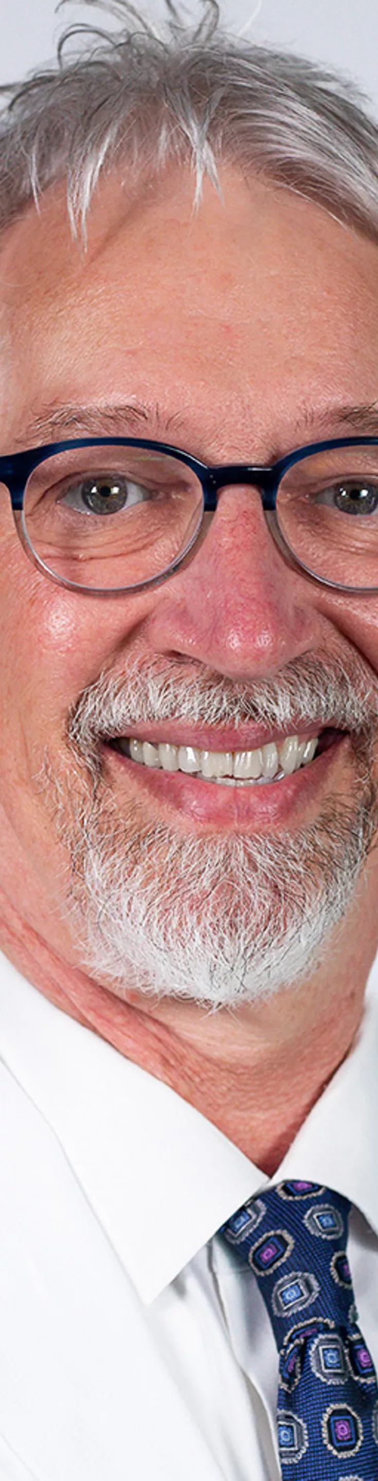 Headshot of Lloyd Berg. He is wearing a dress shirt, blue tie, and a white coat.