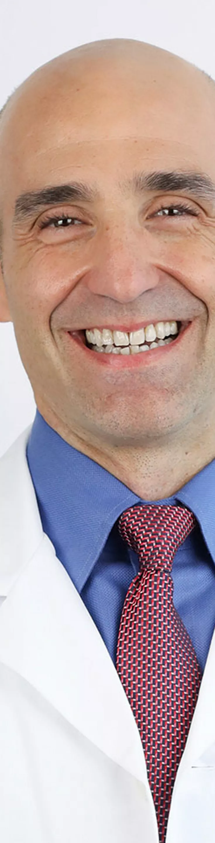 Headshot of Mark Queralt.  He is wearing a white coat and a red tie.