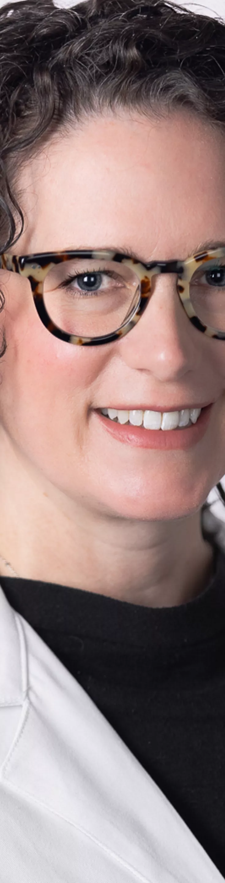 Headshot of Megan Klien. She is wearing a black blouse and a white coat.