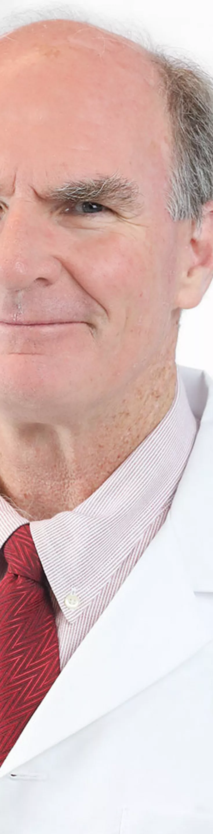 Headshot of Michael Breen.  He is wearing a white coat and a red tie.