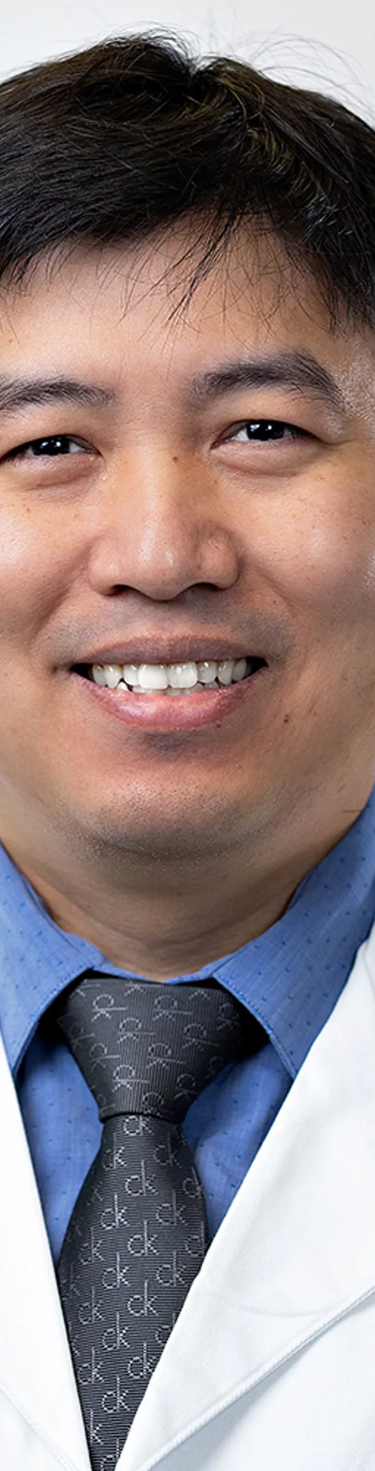 Headshot of Moe Hein Aung. He is wearing a blue dress shirt, a gray tie, and a white coat.