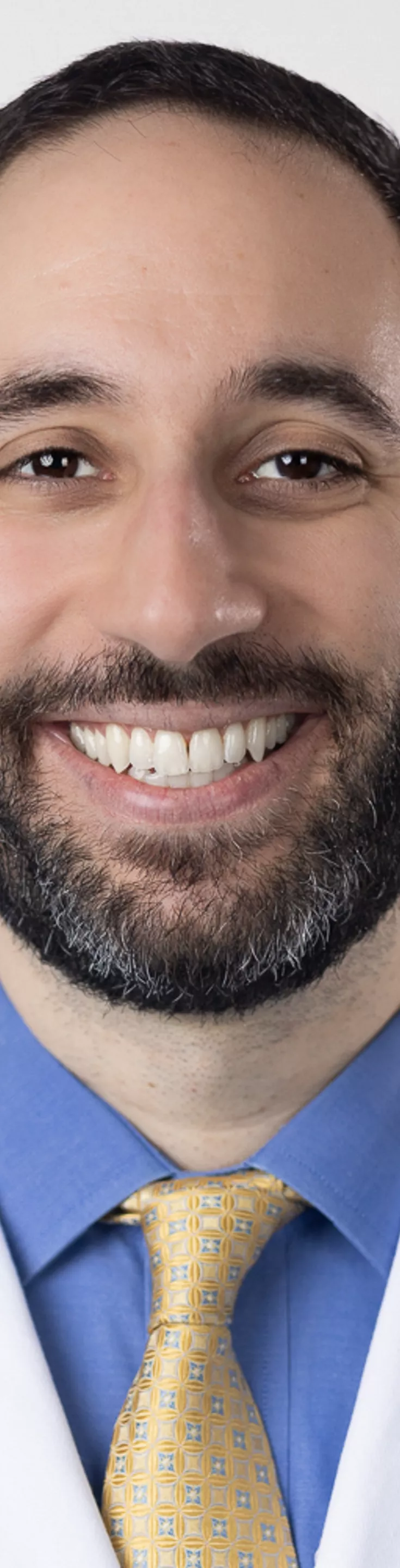 Headshot of Navid Valizadeh. He is wearing a blue dress shirt, a yellow tie, and a white coat.