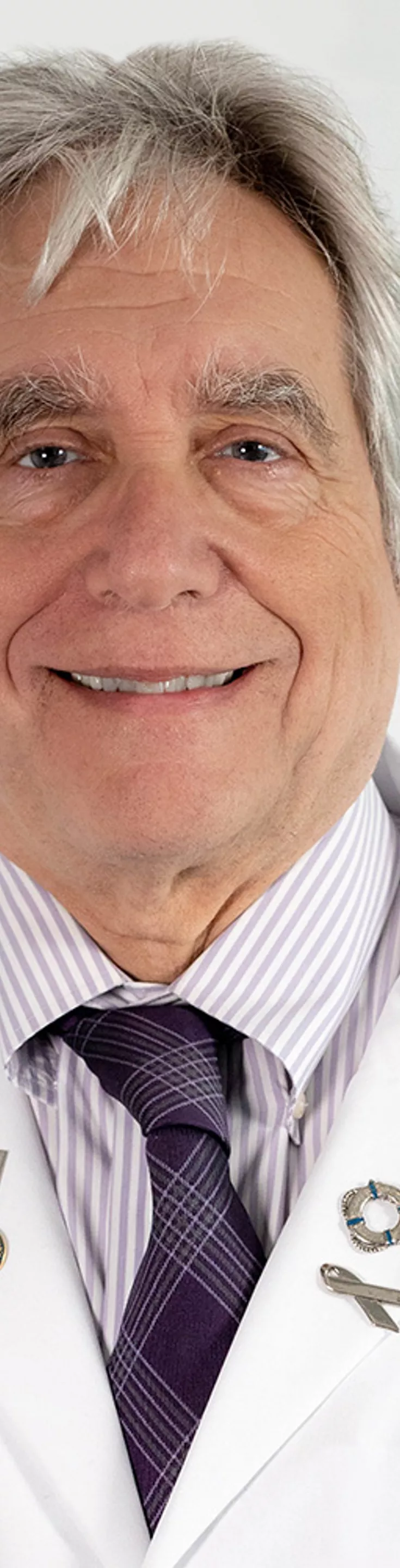 Headshot of Charles Nemeroff. He is wearing a striped purple shirt, a purple tie, and a white coat.