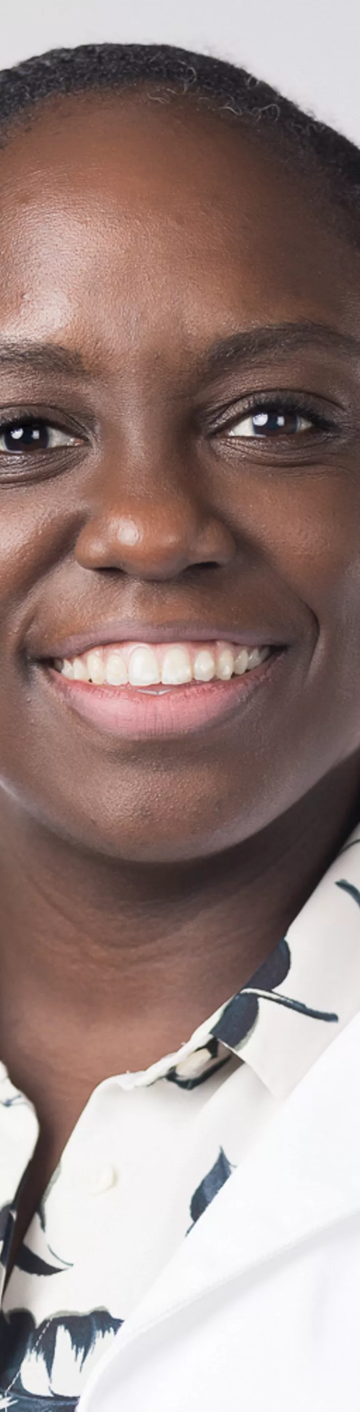 Headshot of Nerlyne Desravines. She is wearing a black and white floral blouse and a white coat.
