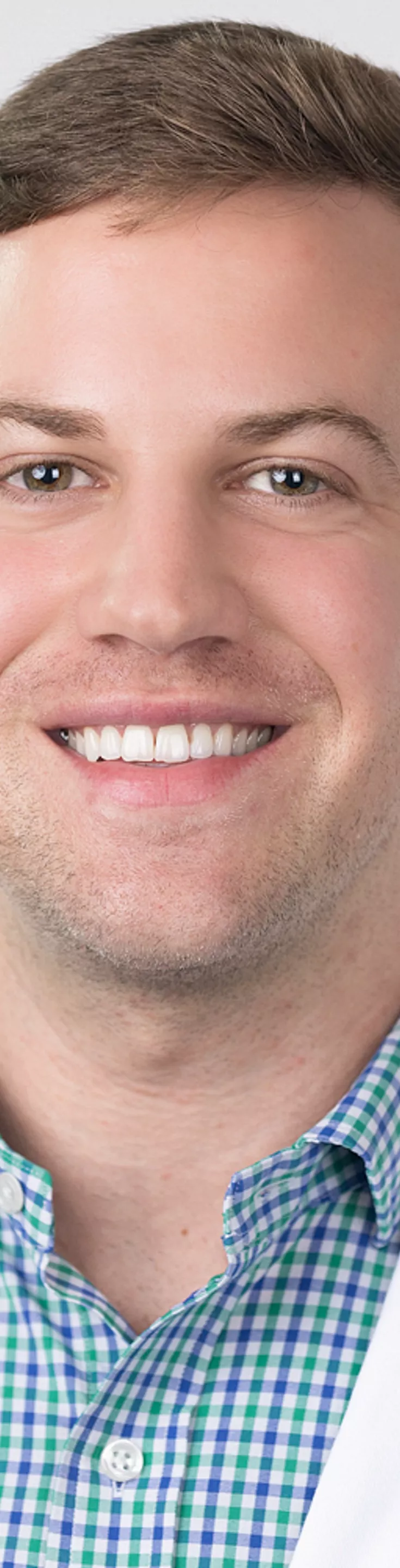 Headshot of Patrick LaBrode. He is wearing a blue and green plaid dress shirt and a white coat.
