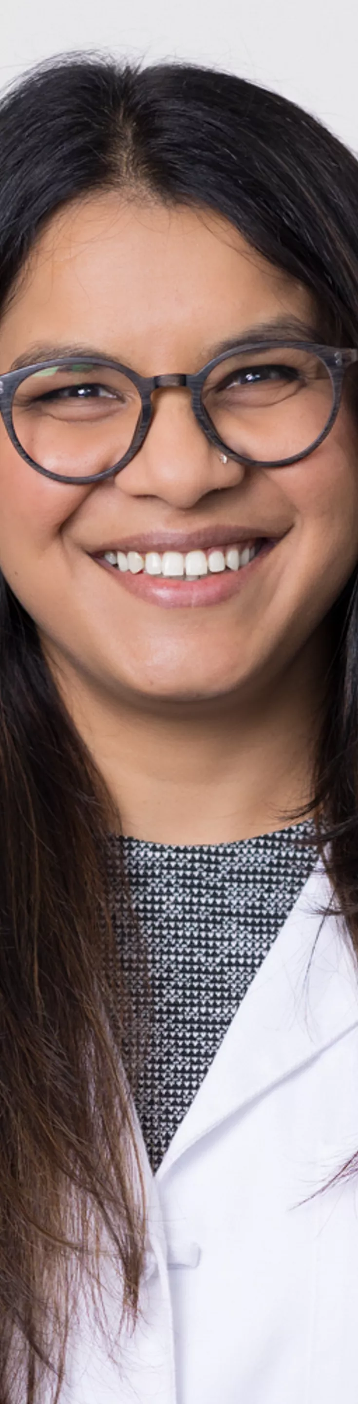 Headshot of Saleema Kherani. She is wearing a black and white blouse and a white coat.