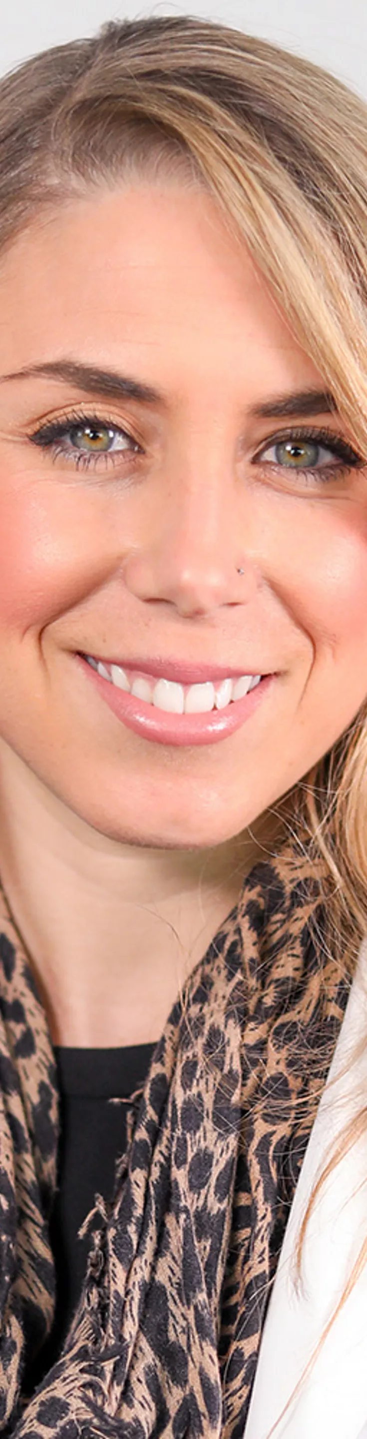 Headshot of Sarah Felderhoff. She is wearing a black blouse, leopard print scarf, and a white coat.