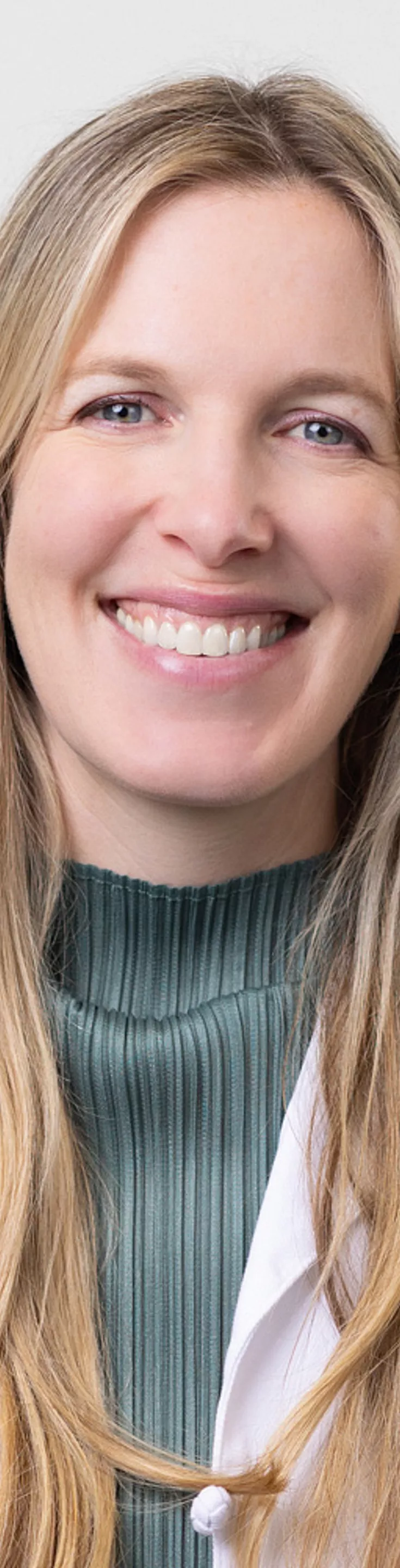 Headshot of Sarah Vij. She is wearing a green blouse and a white coat.