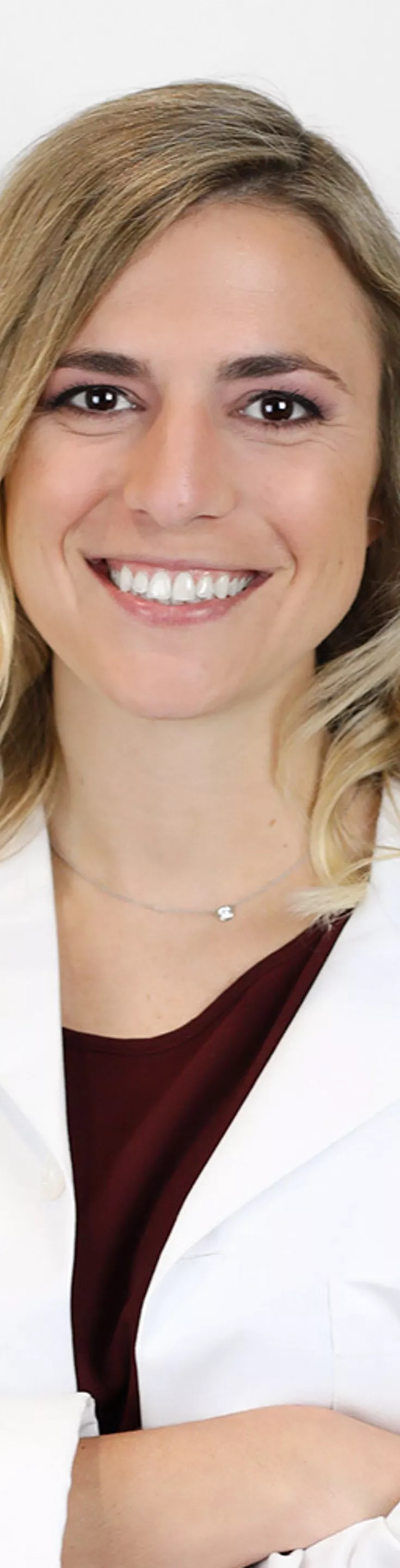 Headshot of Stephanie Doggett.  She is wearing a white coat and a maroon blouse.