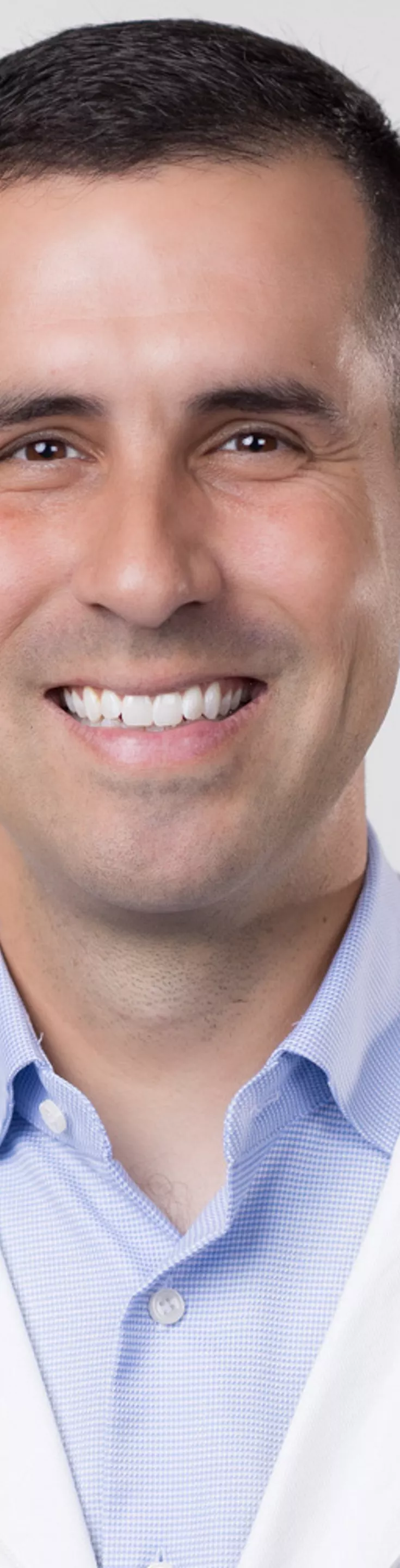 Headshot of Sullivan Ayuso. He is wearing a blue dress shirt and a white coat.