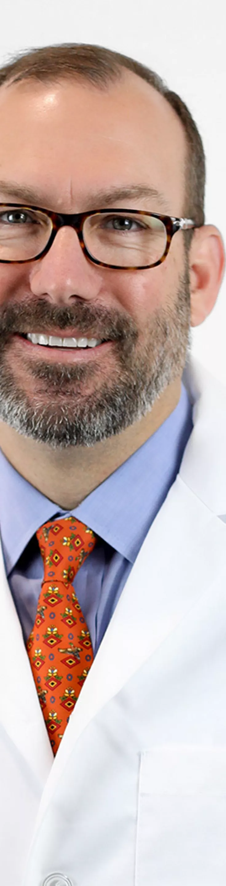 Headshot of Tripp Buckley.  He is wearing a white coat and an orange tie.