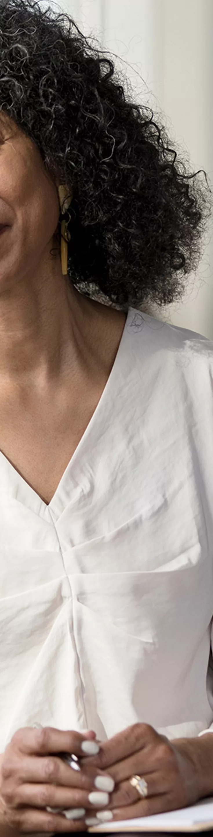 Two women are seated facing each other in a contemporary office environment. One woman holds a clipboard, suggesting a professional or counseling discussion. 