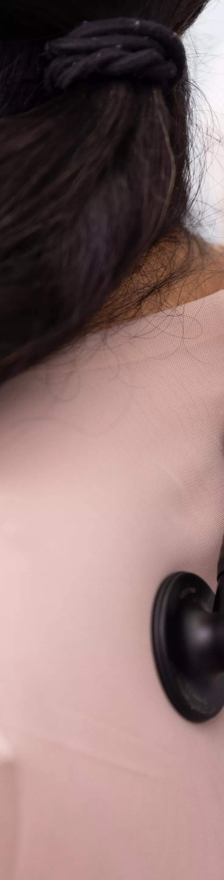 A healthcare professional is using a stethoscope to listen to the back of a seated patient. The setting appears to be a medical office or clinic, with the focus on the examination process. The patient has long dark hair and is wearing a light-colored top, while the doctor's white coat is partially visible.