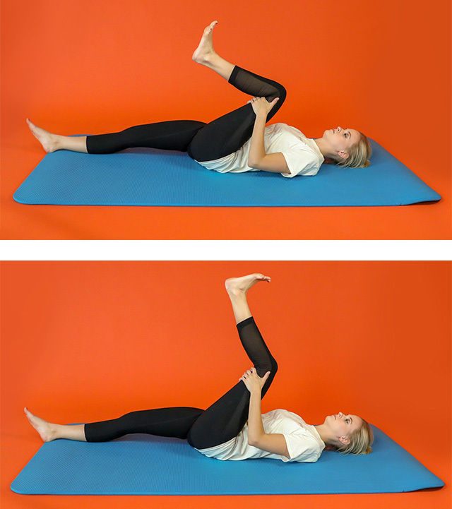 A young woman is shown lying on her back on a blue exercise mat, demonstrating a leg stretch in two stages. The setting features a solid orange background, emphasizing the subject and her movements. She wears a white t-shirt and black leggings, and the exercise appears to focus on flexibility and lower body stretching. No visible text or numbers are present in the image.