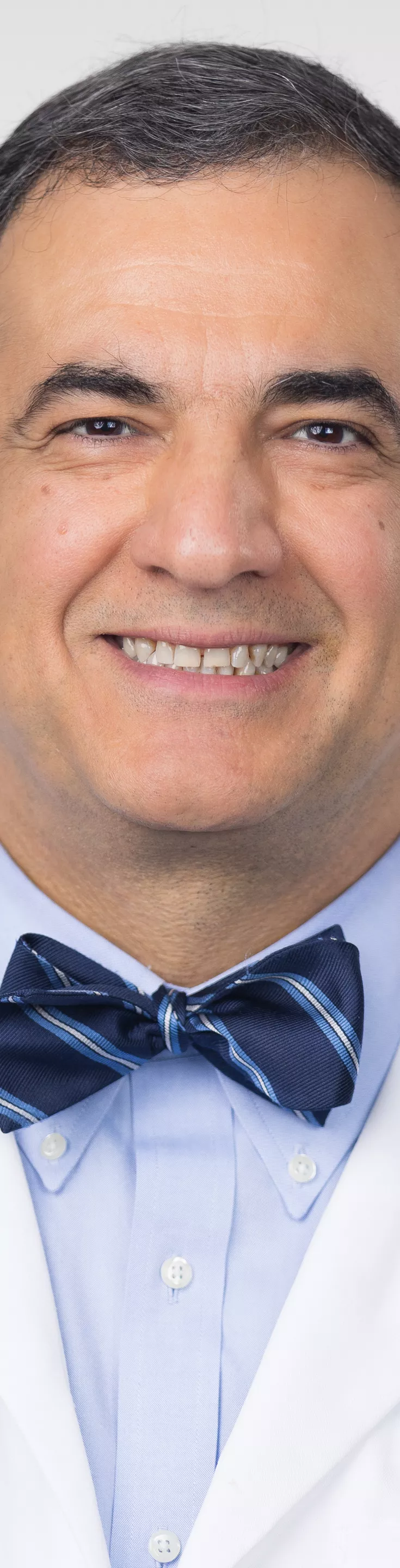 Headshot of Mehdi Misraeidi. He is wearing a light blue dress shirt, a navy striped bowtie, and a white coat.