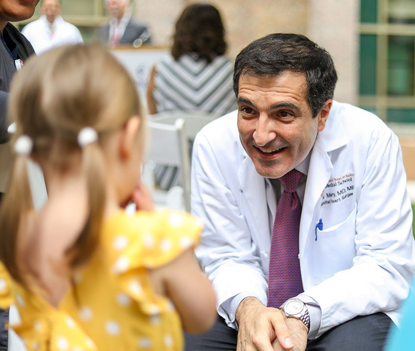 A mother holds her baby up to a smiling doctor holding a stethoscope.