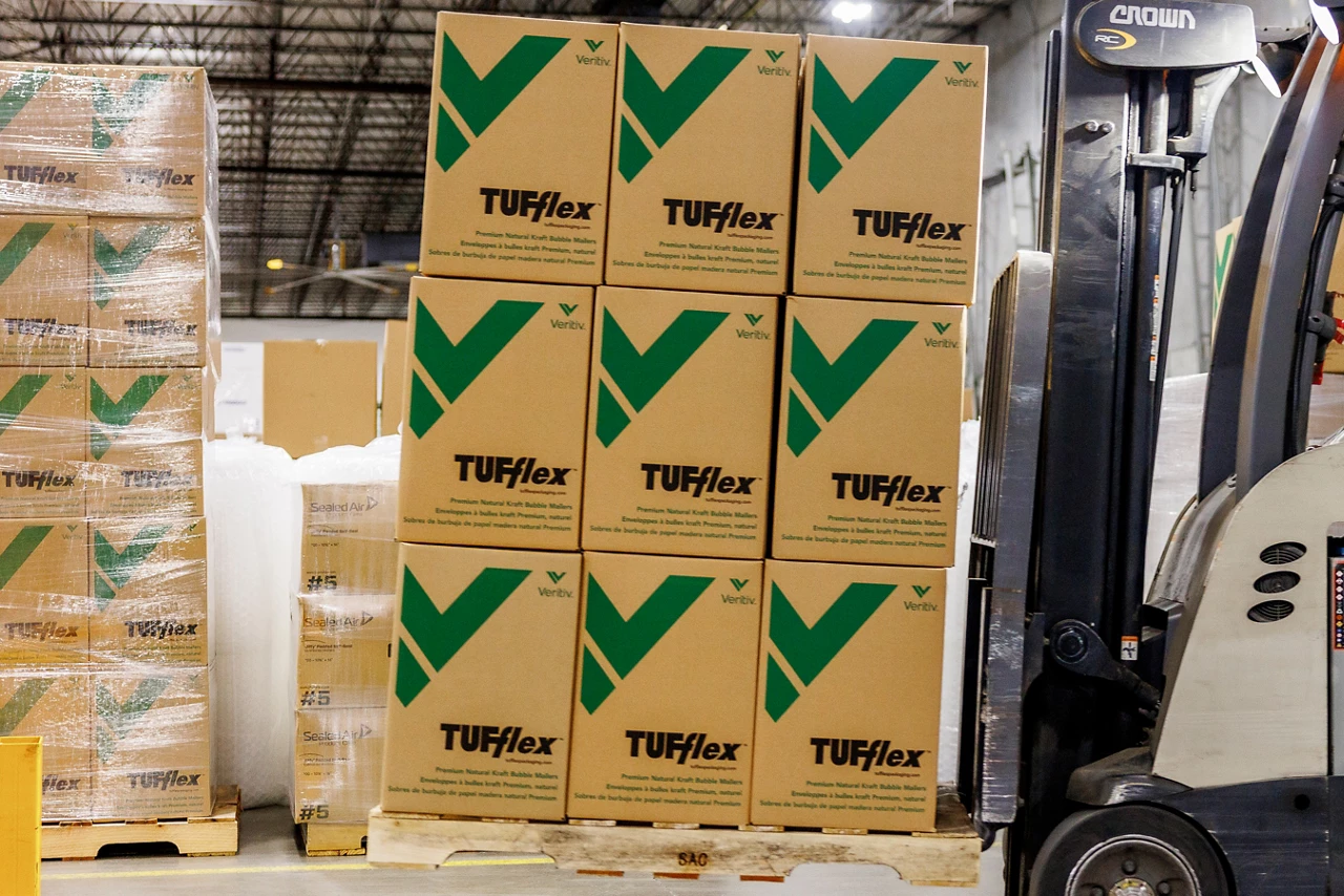 Forklift carrying a pallet of boxes with the TUFflex logo.