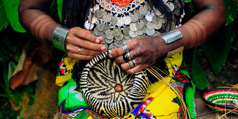 Woman weaving basket in vibrant attire