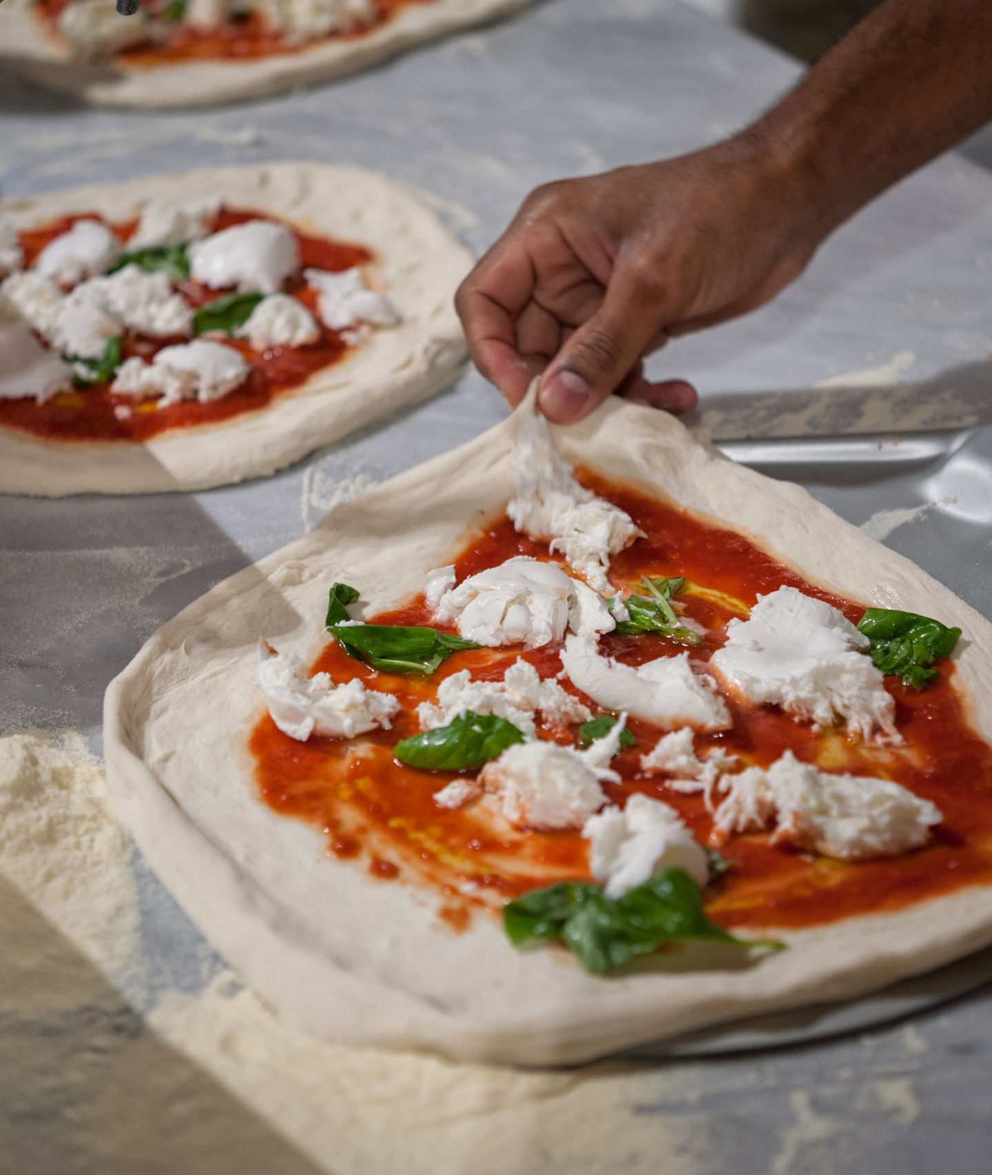 Preparing fresh pizza with mozzarella and basil